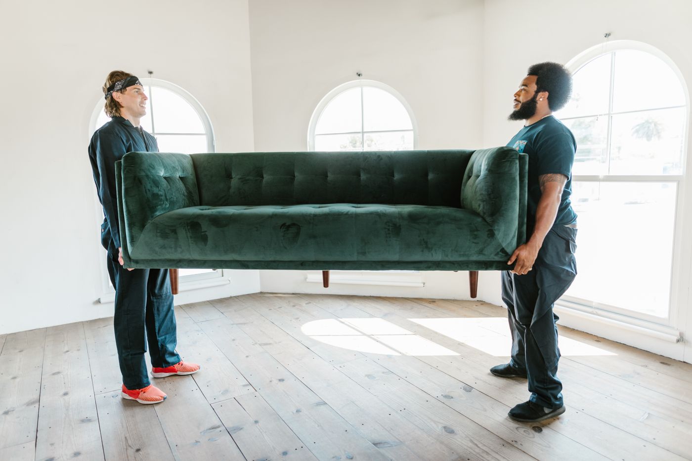 Two movers carrying a green sofa