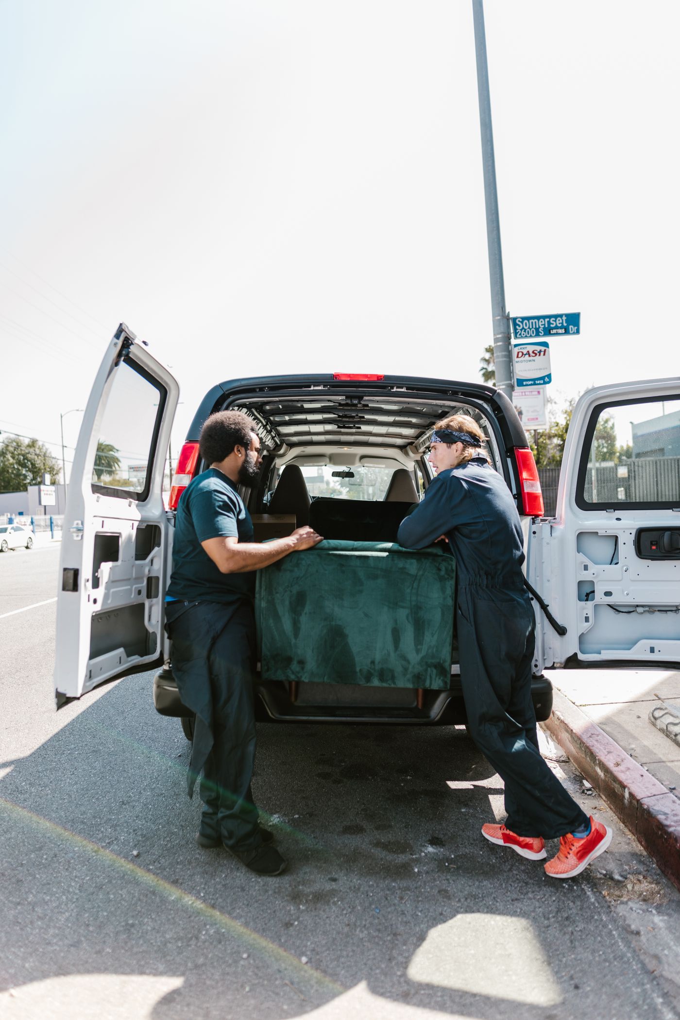 Two movers loading a sofa into a van